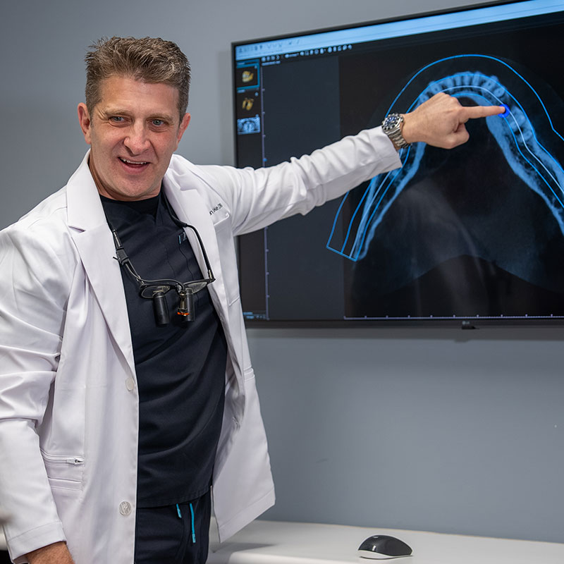 Dr. tooke pointing at tooth xray on TV
