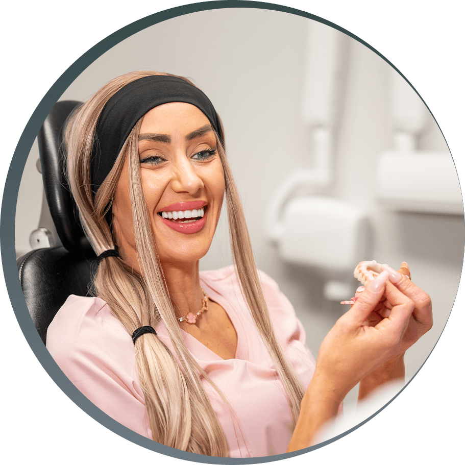 Lacie - dental implant patient smiling and holding full arch dental implant model